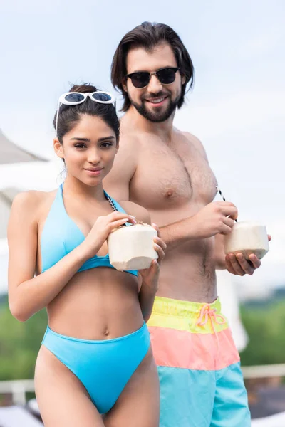 Young beautiful couple in sunglasses holding coconut cocktails — Stock Photo