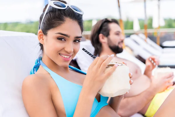 Young couple relaxing on sunbeds with fresh coconut cocktails, selective focus — Stock Photo