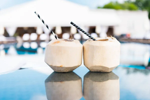 Green coconut cocktails with straws standing on table with reflection — Stock Photo