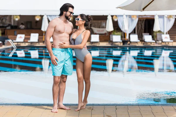 Beautiful couple embracing near swimming pool at summertime — Stock Photo