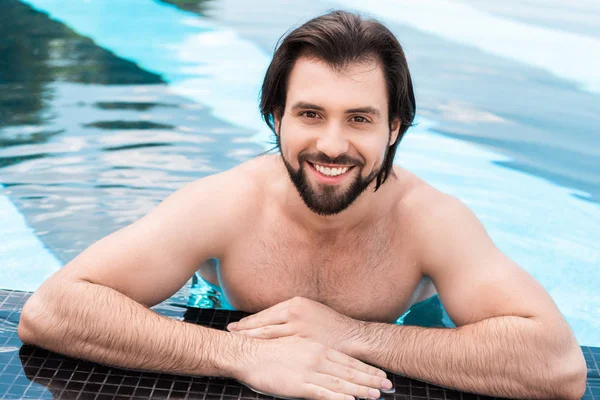 Бородатый улыбающийся мужчина в бассейне смотрит в камеру — стоковое фото