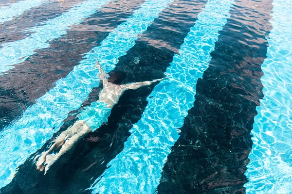 Hombre nadando bajo el agua en la piscina azul - foto de stock