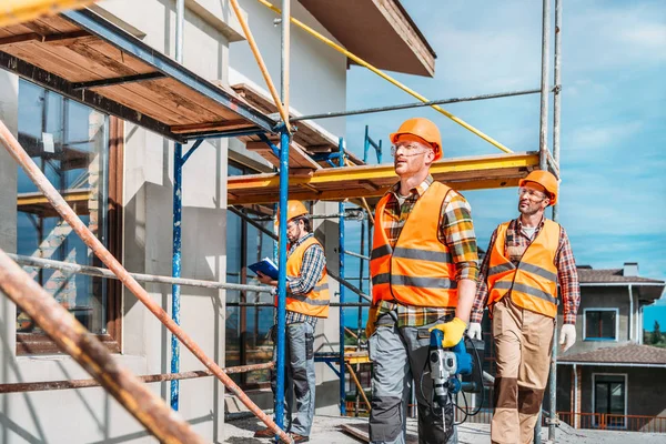 Groupe de beaux constructeurs travaillant ensemble sur le chantier de construction — Photo de stock