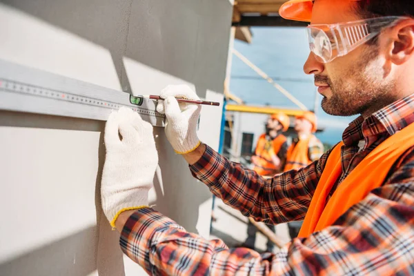 Side view of builder using bubble level at construction site — Stock Photo