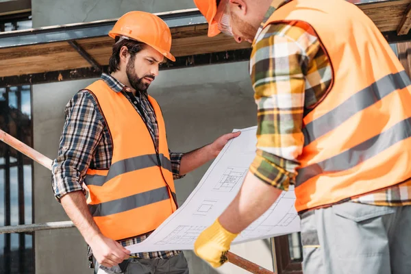 Thoughtful builders with blueprint at construction site — Stock Photo