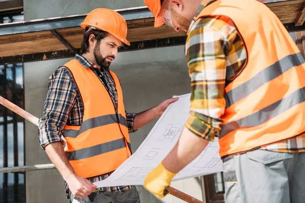 Nachdenkliche Bauherren mit Bauplan auf Baustelle — Stockfoto