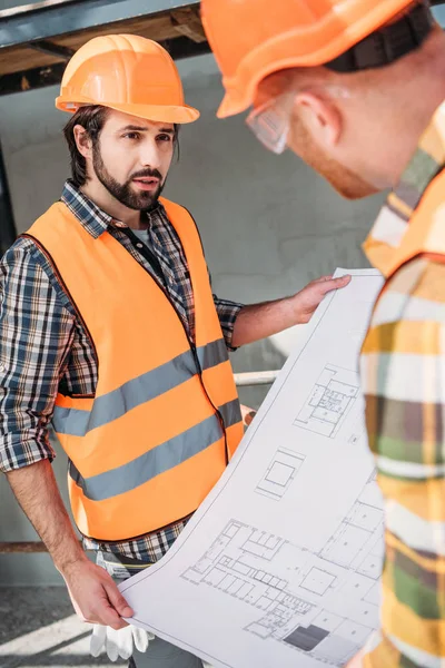 Bauarbeiter mit Bauplan unterhalten sich auf Baustelle — Stockfoto