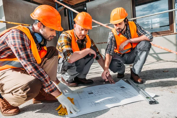 Nahaufnahme einer Gruppe von Bauarbeitern im Gespräch über den Bauplan — Stockfoto
