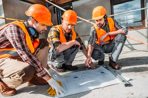 Gros plan du groupe de constructeurs ayant une conversation sur le plan de construction — Photo de stock