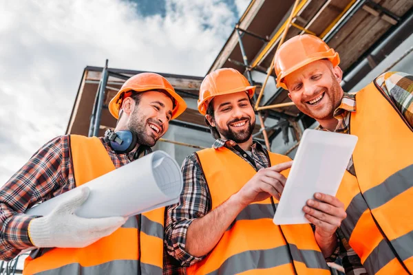 Baugruppe mit Bauplan und Tablet auf der Baustelle — Stockfoto