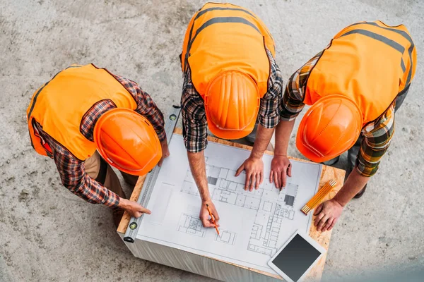 Visão de alto ângulo do grupo de construtores discutindo o plano de construção no canteiro de obras — Fotografia de Stock