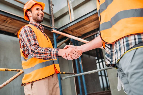Plan recadré de constructeurs serrant la main sur le chantier de construction — Photo de stock