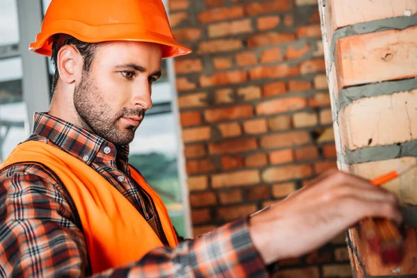 Hübscher junger Bauarbeiter misst auf Baustelle — Stockfoto