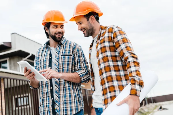 Arquitetos com planta e tablet trabalhando juntos no canteiro de obras — Fotografia de Stock