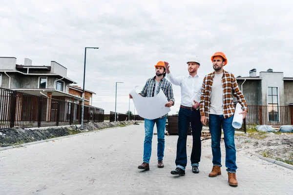 Группа архитекторов, идущих по строительству улицы с чертежами — стоковое фото