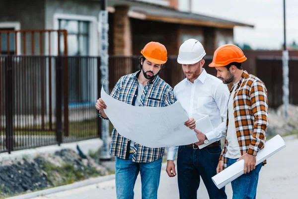 Group of architects standing on building street with blueprints — Stock Photo