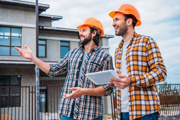 Zufriedene Architekten mit digitalem Tablet, das auf Baustelle zeigt — Stockfoto