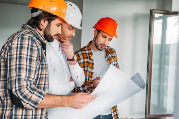 Group of architects with blueprint inside of constructing building — Stock Photo