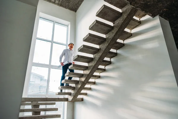 Bello architetto in camicia bianca andando al piano di sopra all'interno della casa di costruzione — Foto stock