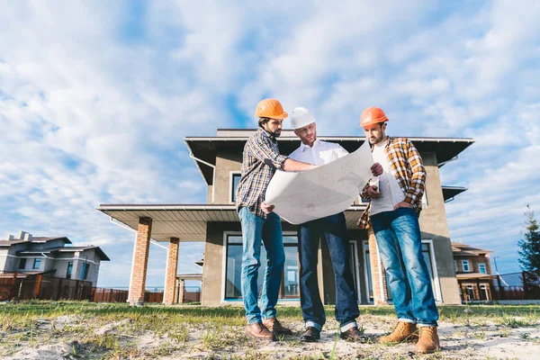 Bottom view of group of architects with blueprint in garden at construction site — Stock Photo