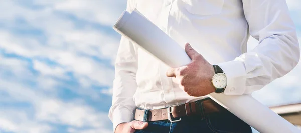 Cropped shot of architect holding blueprints in front of cloudy sky — Stock Photo