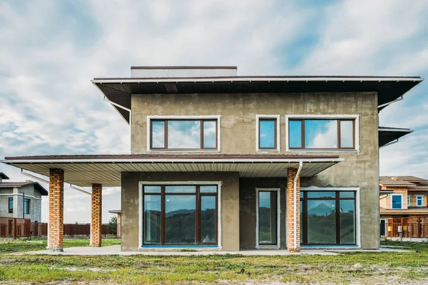 Fassade eines unfertigen modernen Betongebäudes mit begrüntem Hof unter wolkenverhangenem Himmel — Stockfoto