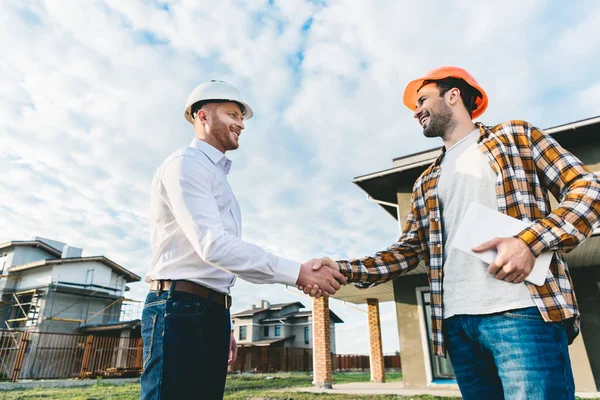 Smiling architects shaking hands in front of construction site — Stock Photo