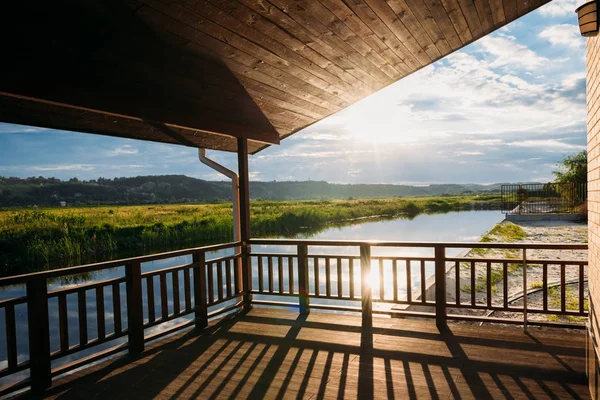 Vue sur le magnifique coucher de soleil sur la rivière depuis la terrasse en bois — Photo de stock