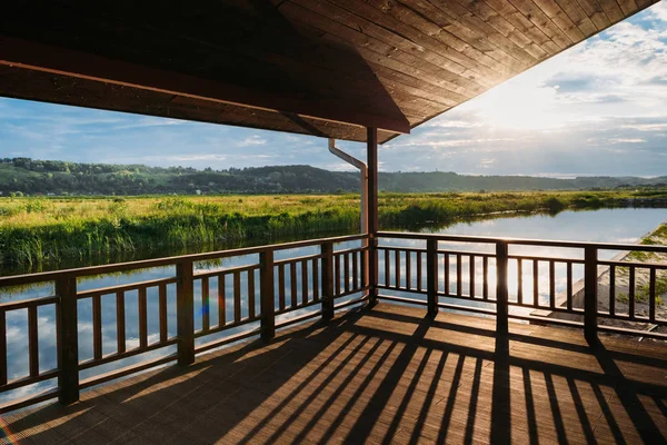 Vue sur le coucher de soleil panoramique sur la rivière depuis la terrasse en bois — Photo de stock