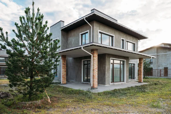 Bâtiment moderne en béton avec cour verte sous un ciel nuageux — Photo de stock