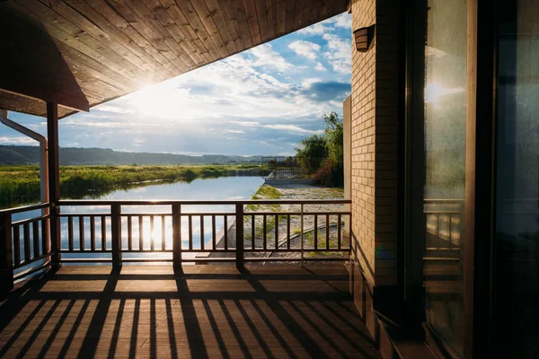 Vue panoramique sur le magnifique coucher de soleil sur la rivière depuis la terrasse en bois — Photo de stock