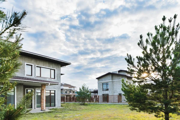 Edificios modernos inacabados con patios verdes en día nublado con abetos en primer plano - foto de stock