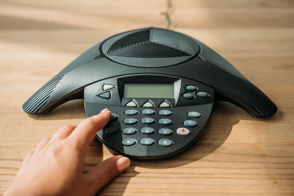 Tiro cortado de mulher de negócios com unhas cor-de-rosa empurrando botão de telefone conferência no local de trabalho — Fotografia de Stock