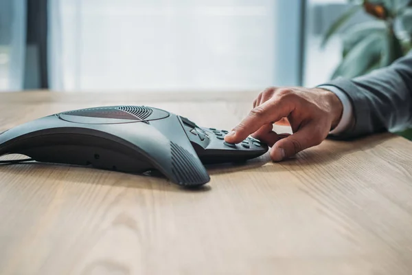 Side view cropped shot of businessman pushing button of conference phone at workplace — Stock Photo