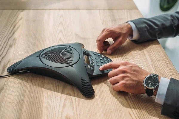 Plan recadré de l'homme d'affaires appuyant sur le bouton du téléphone de conférence sur la table — Photo de stock