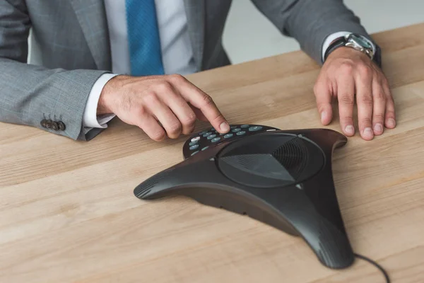 Plan recadré de l'homme d'affaires appuyant sur le bouton de haut-parleur sur le lieu de travail — Photo de stock