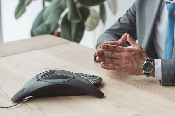 Tiro cortado de empresário sentado usando telefone conferência no local de trabalho — Fotografia de Stock