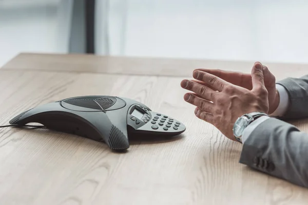 Cropped shot of businessman sitting using conference phone at workplace — Stock Photo