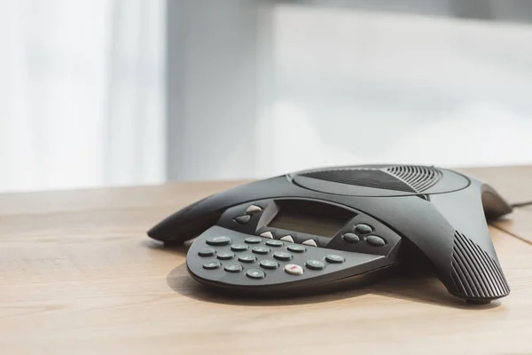 Close-up shot of conference phone on wooden table at office — Stock Photo