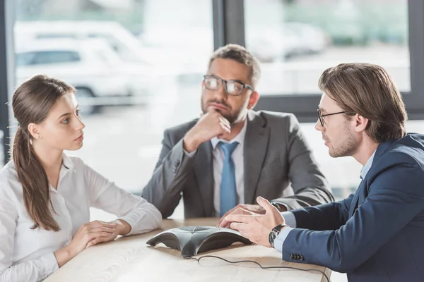 Confident serious business people using conference phone at modern office — Stock Photo