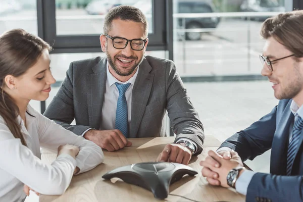 Happy business people using conference phone at modern office — Stock Photo