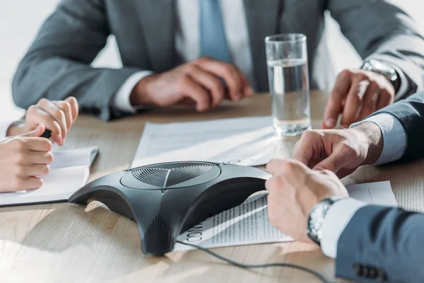 Plan recadré de gens d'affaires assis autour du téléphone de conférence au bureau moderne — Photo de stock