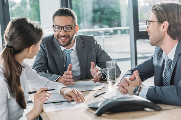 Des gens d'affaires confiants ayant une conversation et utilisant haut-parleur au bureau moderne — Photo de stock