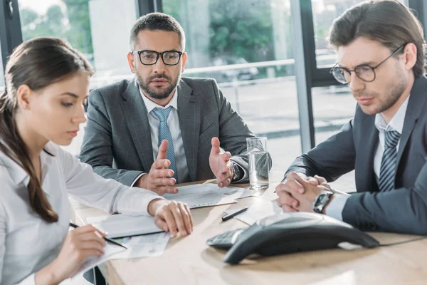 Des gens d'affaires confiants ayant une conversation et utilisant haut-parleur au bureau moderne — Photo de stock