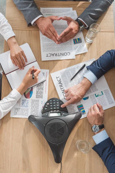 Cropped shot of business people working with documents and speakerphone on table at modern office — Stock Photo