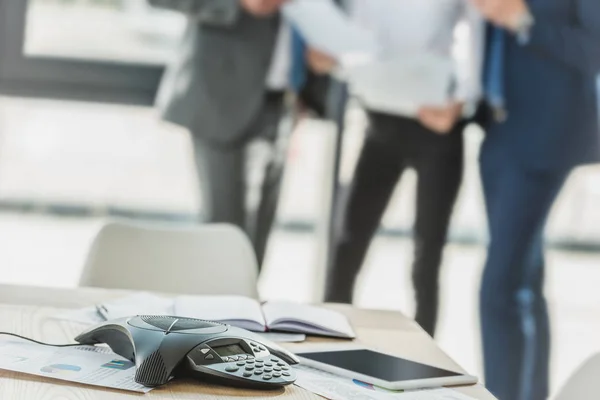 Close-up shot of speakerphone with blurred business people on background at modern office — Stock Photo