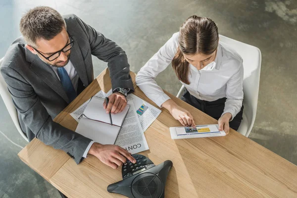 High angle view of businessman and businesswoman with tablet and speakerphone working together at modern office, booking website on screen — Stock Photo