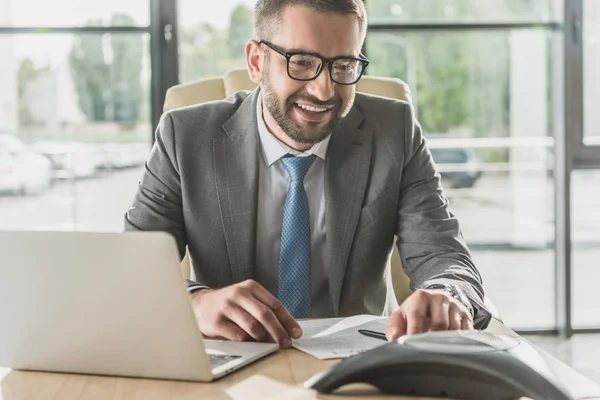 Bonito sorridente empresário usando alta-voz no escritório moderno — Fotografia de Stock