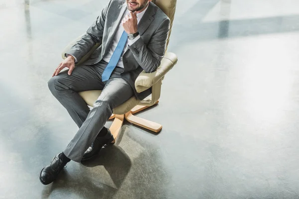 Plan recadré d'un bel homme d'affaires assis sur un fauteuil de luxe au bureau moderne — Photo de stock