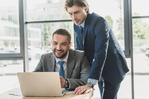 Handsome successful business people working with laptop together at modern office — Stock Photo